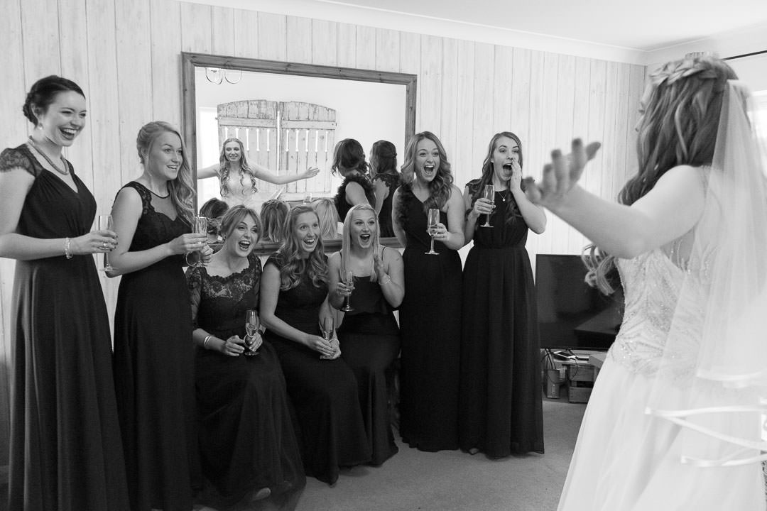 the bride shows her bridesmaid squad the dress