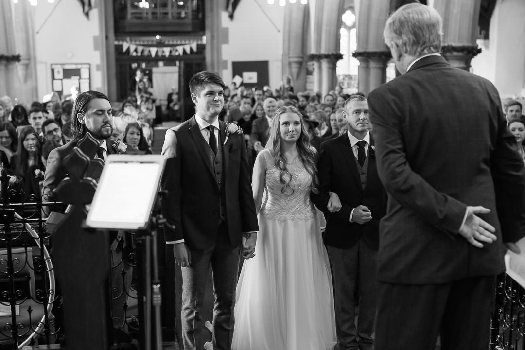 bride and groom stand before the vicar at St Michael's church in Camberley