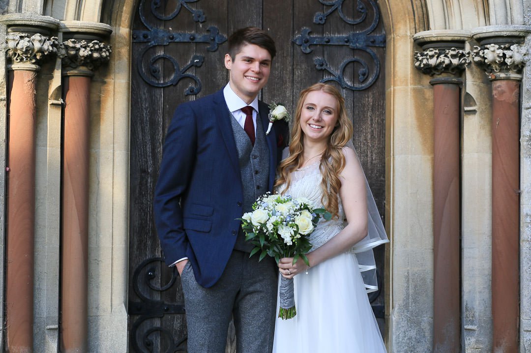 bride and groom pose outside St Michael's church in Camberley