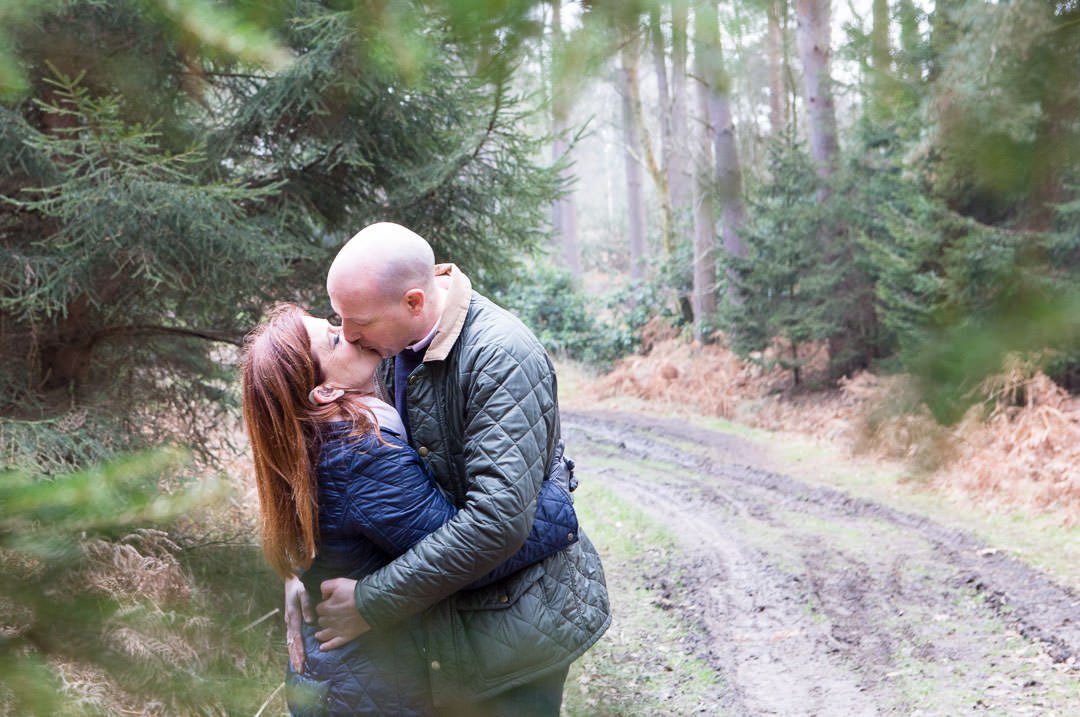 engagement photography session in Swinley forest - couple enjoy a kiss in the woods