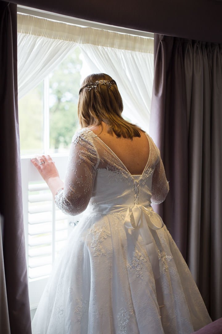 The bride looks out of the window at Oakley Hall in Hampshire