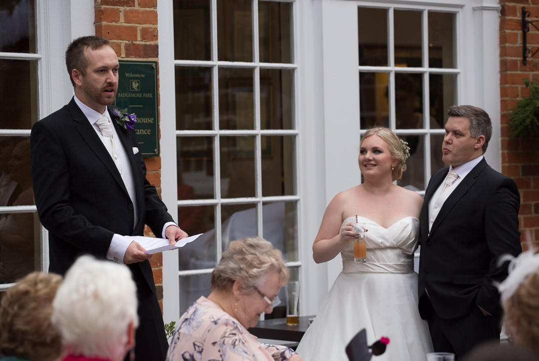 Bride and groom listen to speeches at Badgemore Park in Berkshire