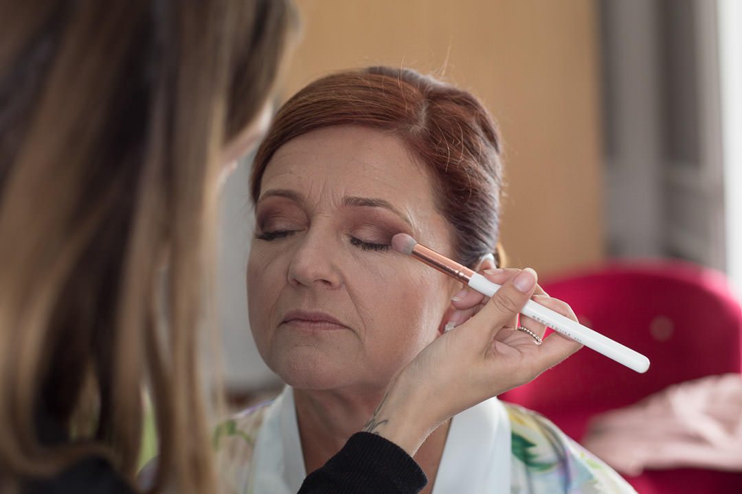 make up artist applies eye shadow to the bride for her wedding makeup 