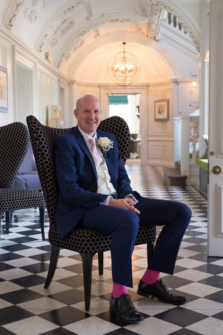 Groom sits on an armchair in the hall at Barnett Hill Hotel