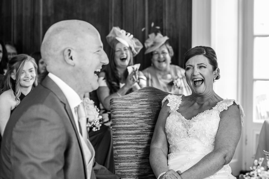 Black and white photo of the bride and groom laughing during the ceremony at Barnett Hill Hotel