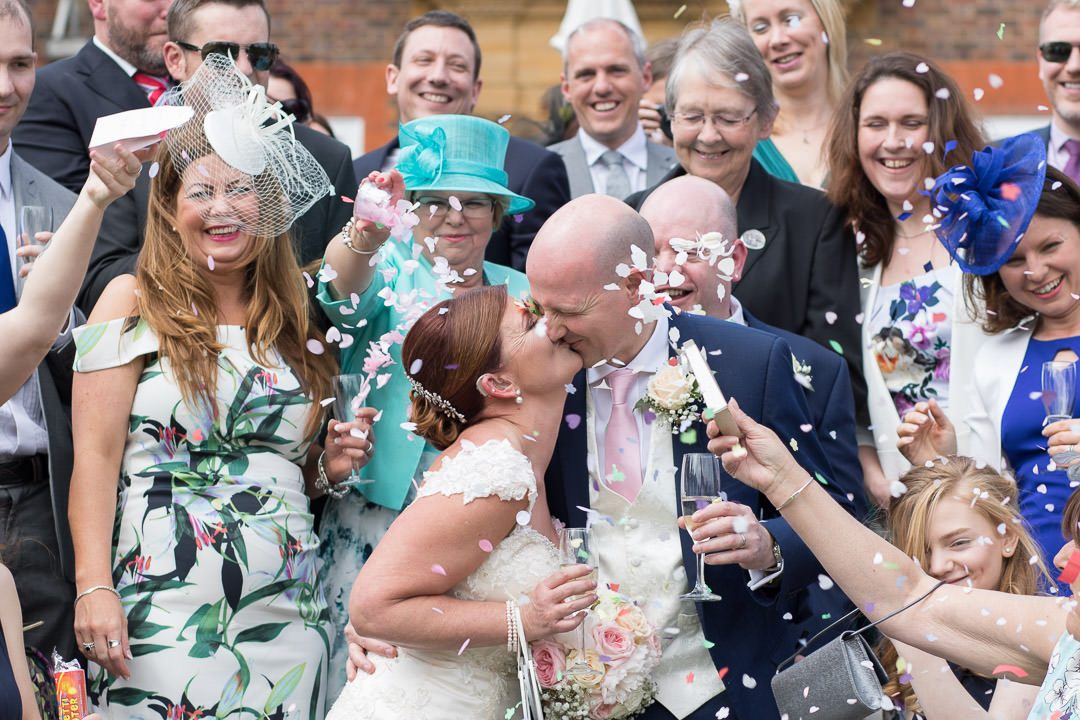 Close up of the bride and groom kissing surrounded by guests throwing confetti at Barnett Hill Hotel