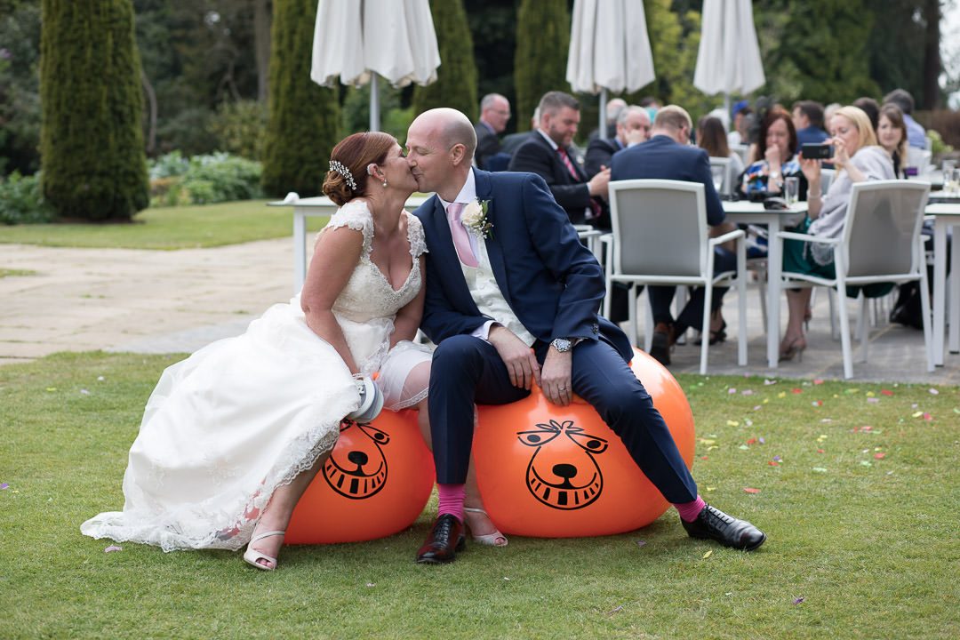 The bride and groom enjoy a kiss on the space hoppers