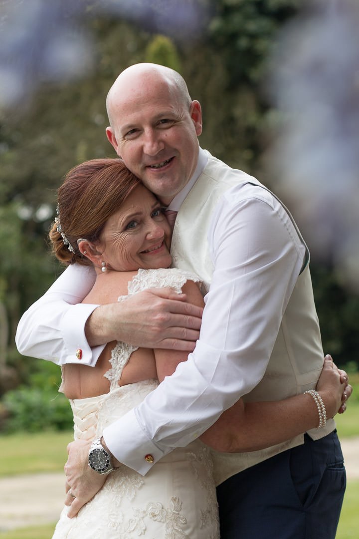 The bride and groom enjoy a hug under the wisteria at Barnett Hill Hotel