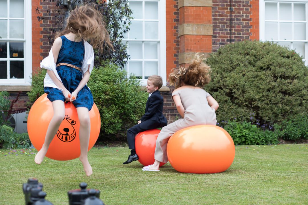 Young wedding guests have fun on the space hoppers 