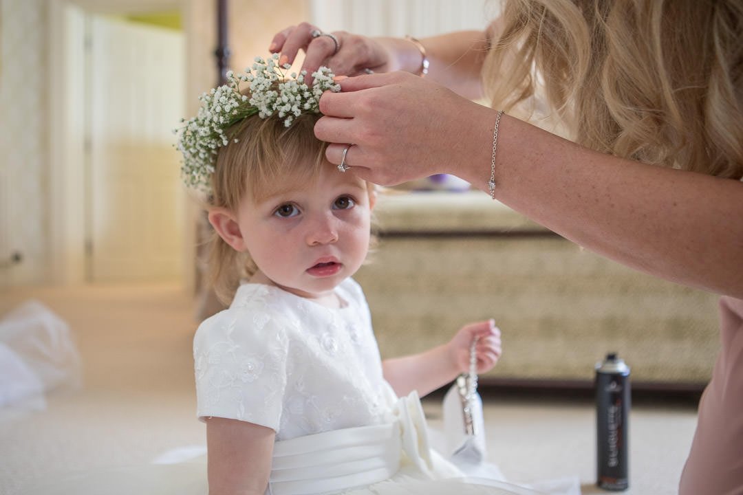 flower girl has her flower crown put on during bridal preparation at the Vineyard in Stockcross, wedding venue near Newbury in Berkshire
