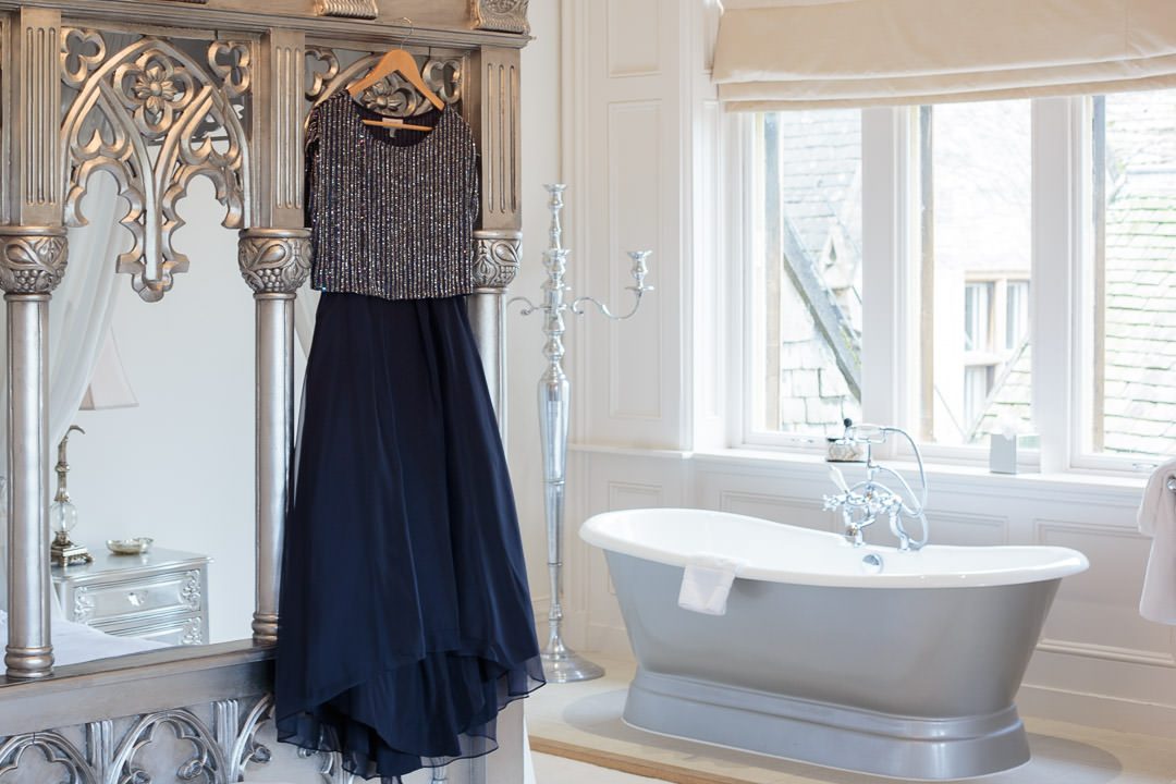 the bride's navy blue dress hangs on the silver four poster bed,