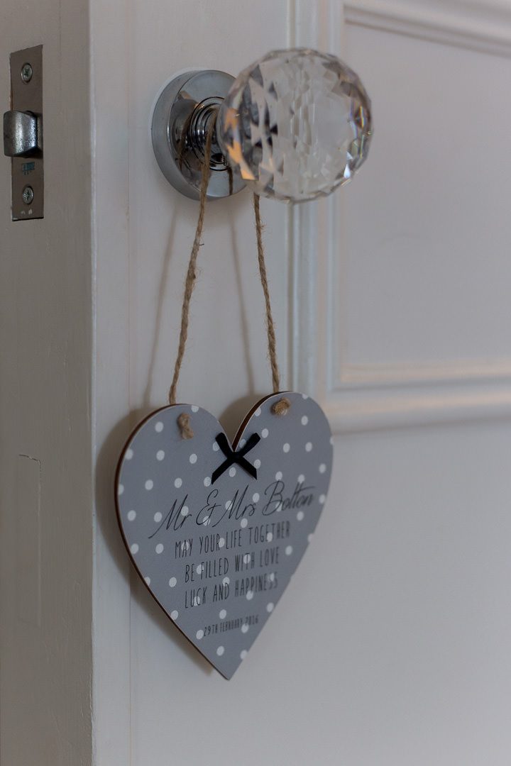 a grey and white spotted wooden heart shaped door hanger on the handle of the door