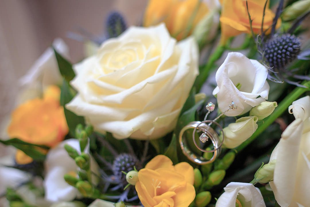 the wedding ring balanced in the yellow, blue and white bouquet