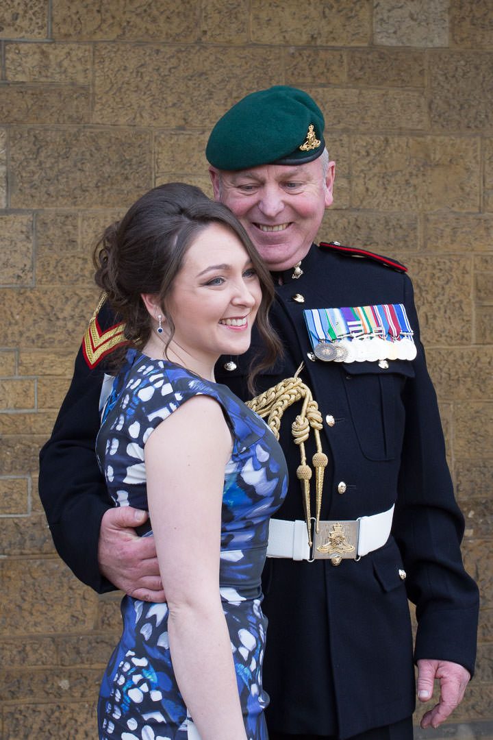 the groom in military dress looks proudly at his adult daughter