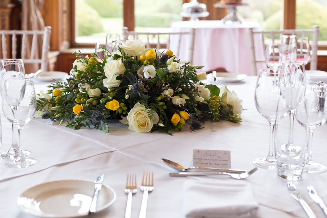 a yellow and white table arrangement on the wedding breakfast table