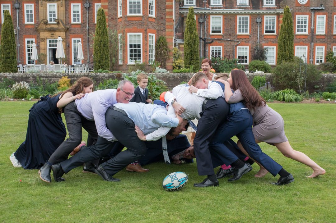 the wedding guests play a game of rugby on the lawn at Barnett hill 
