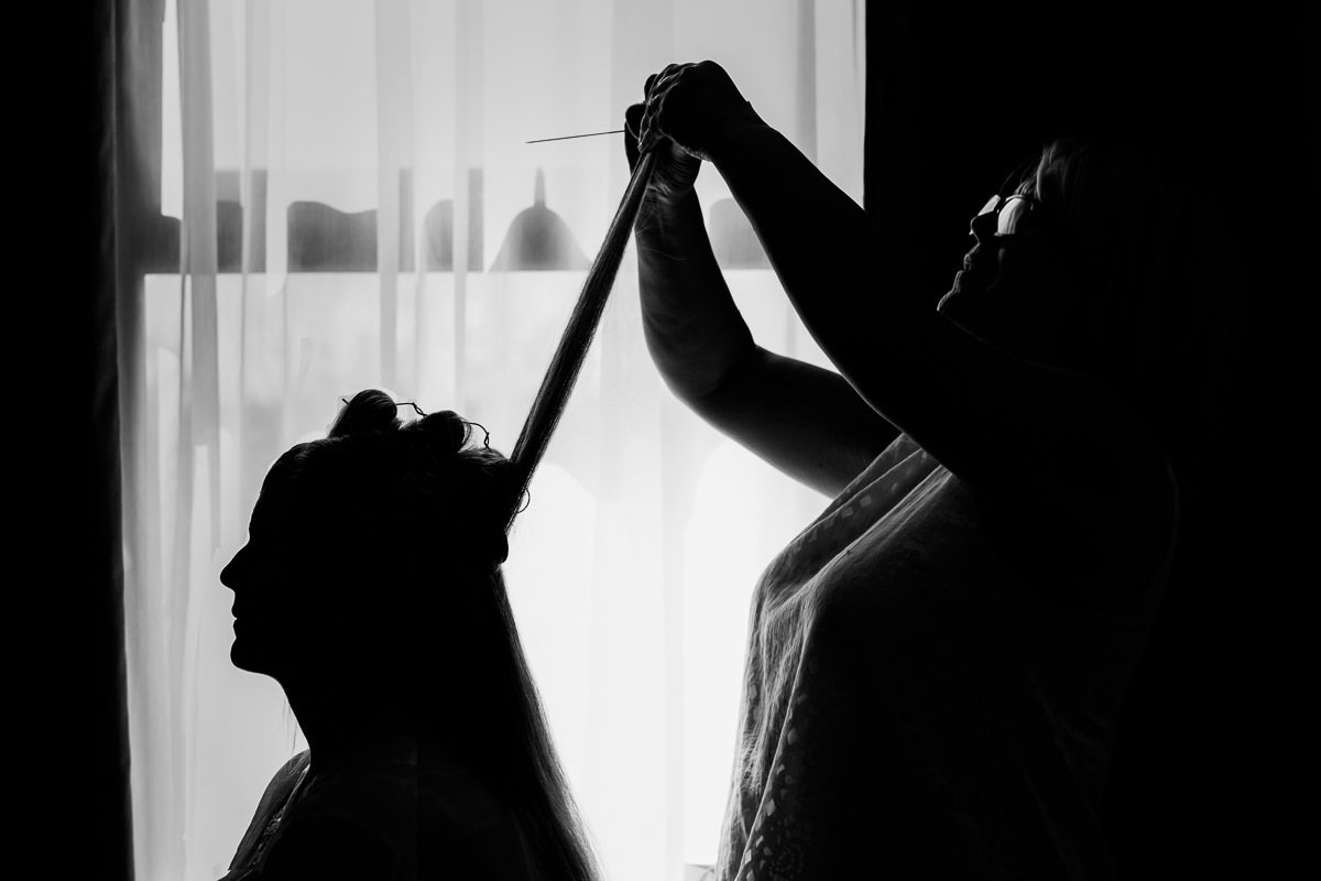 silhouette of bridal prep as the hairdresser puts the bride's hair into rollers