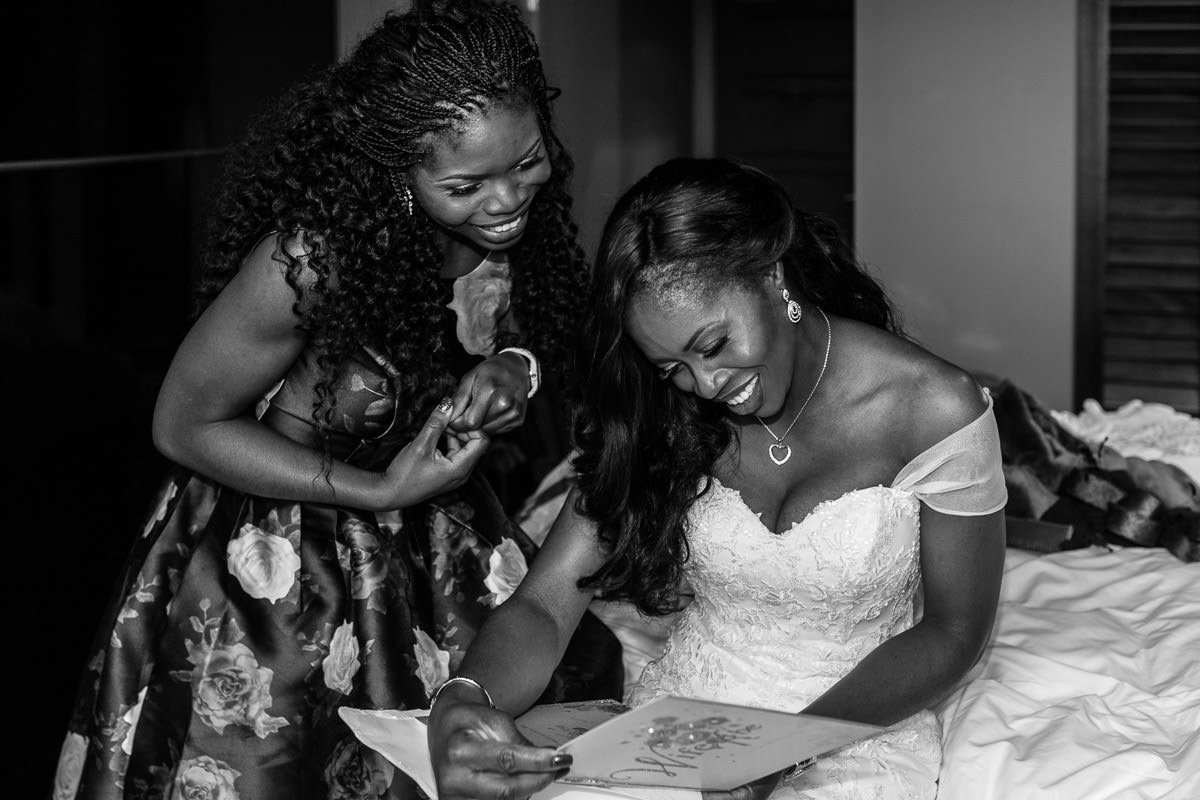 bridesmaid watches as the smiling bride reads a letter from the groom at the village hotel in Farnborough