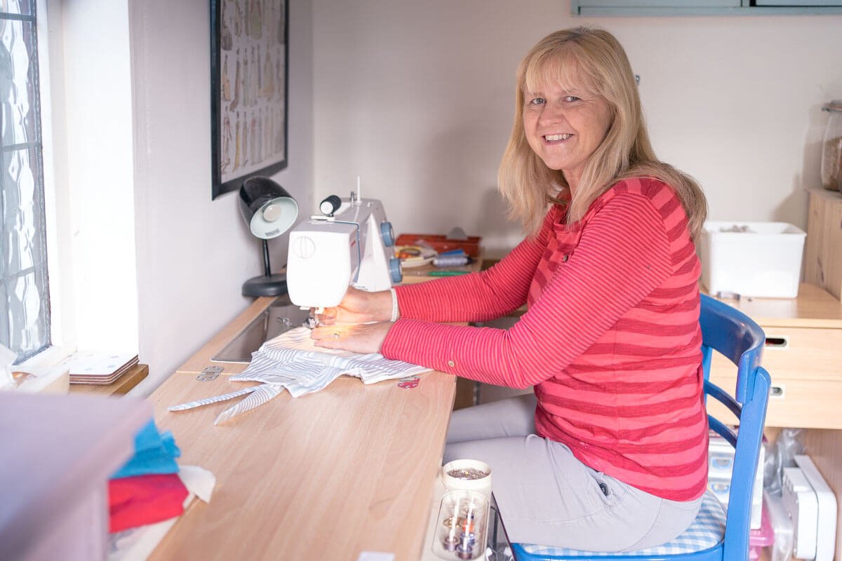 a seamstress sews a stripy garment on her sewing machine