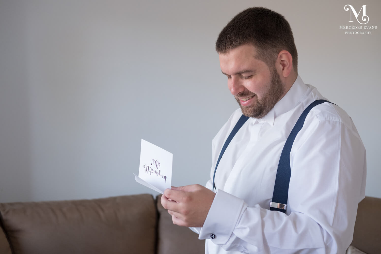 the groom laughs as he reads a card from the bride 