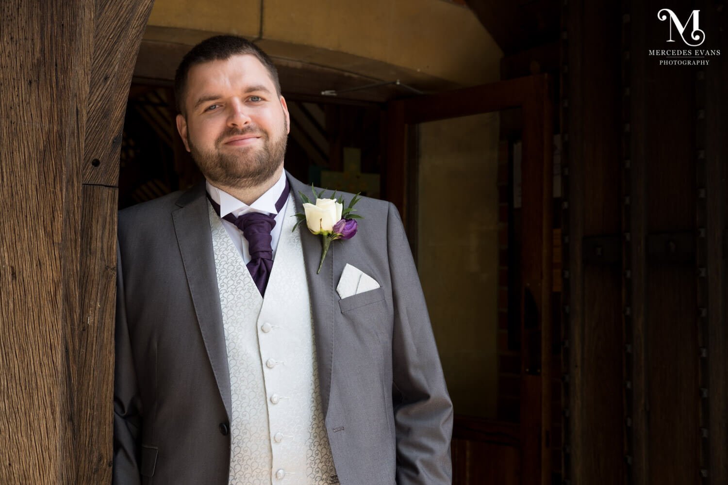 The groom leans against the doorway of St Andrew's church in Frimley