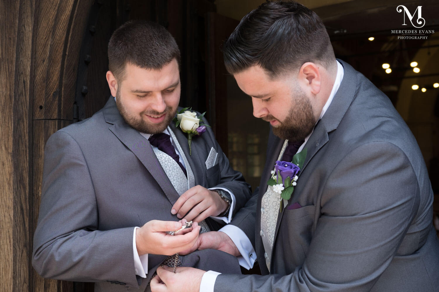 The best man helps the groom with his pocket watch