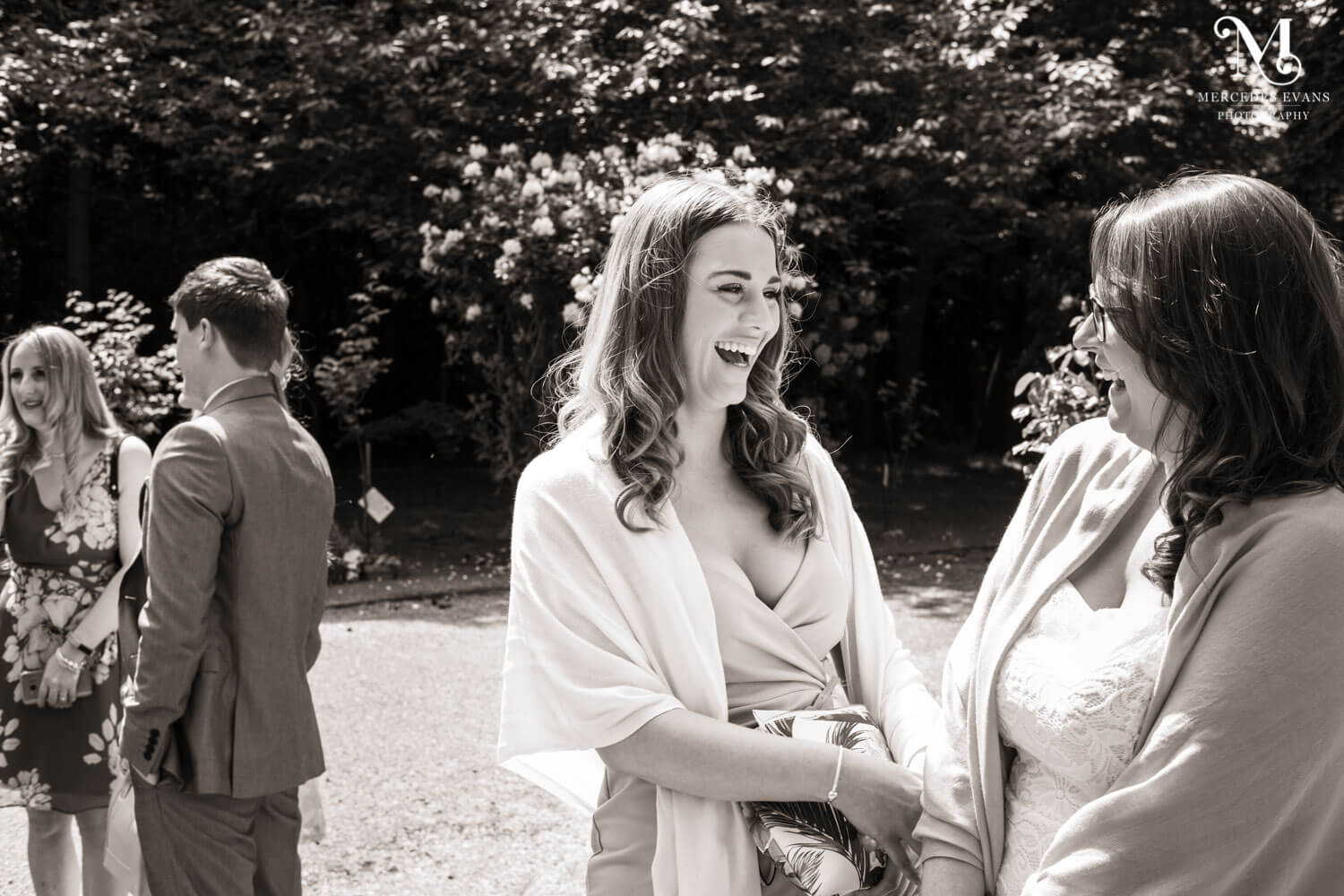 female wedding guests laugh together in the church yard