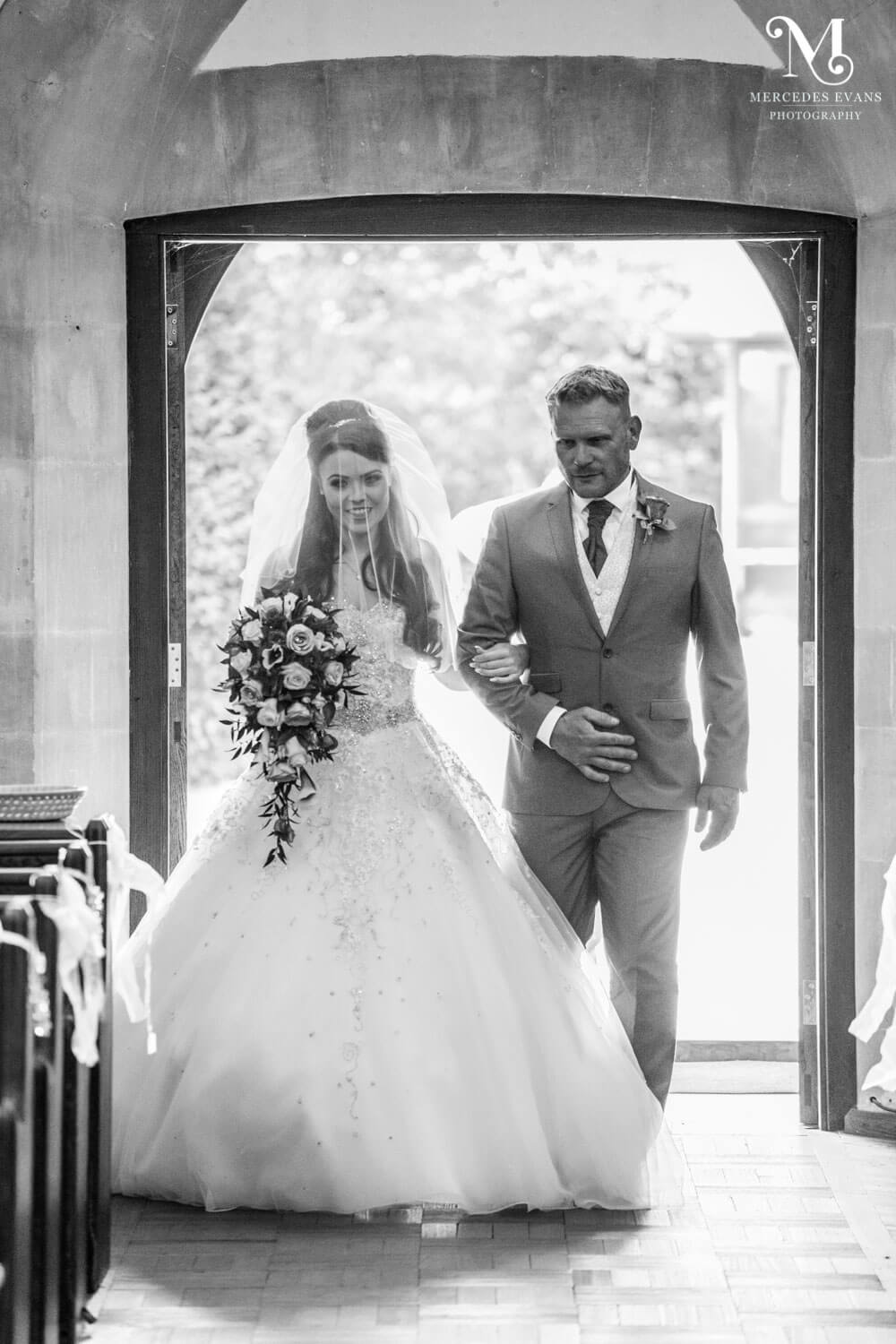 The bride and her uncle walk into St Andrew's church in frimley for the wedding ceremony