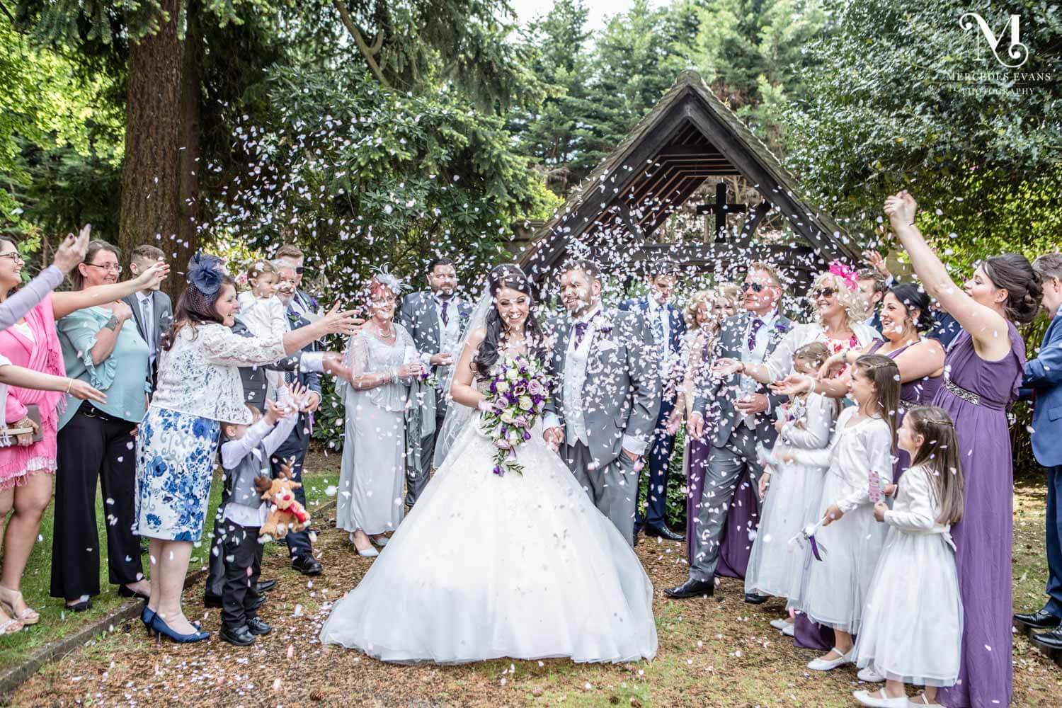 confetti photo in front of the lych gate at St Andrew's church in Frimley