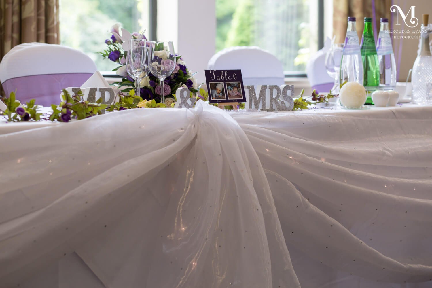 The top table dressed with white organza drapes and mr and mrs letters