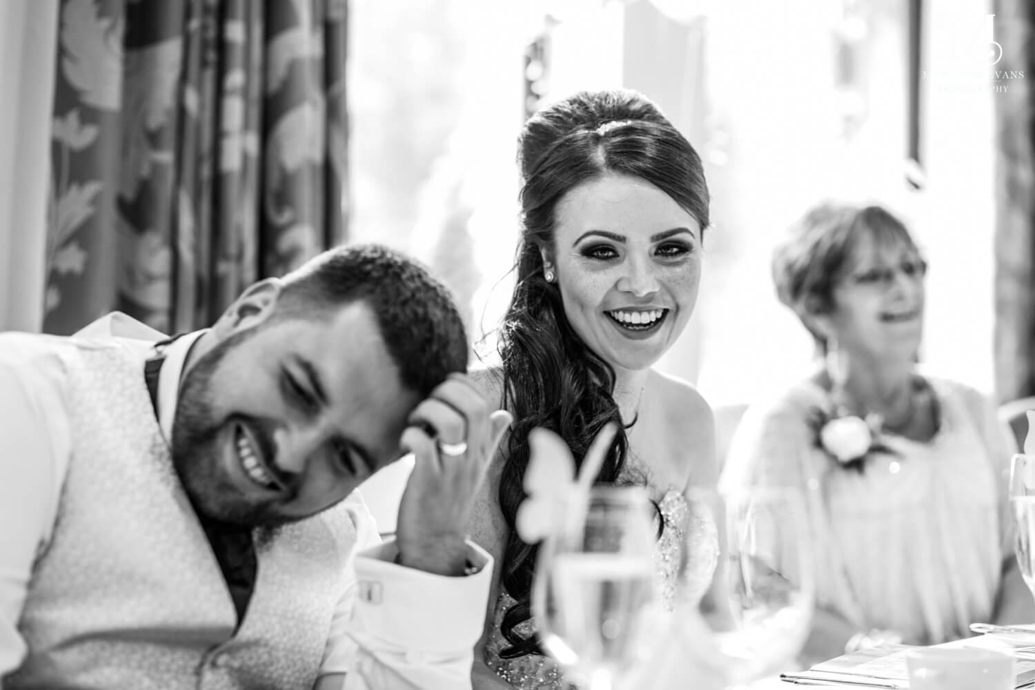 The bride and groom laugh during the best man's speech 