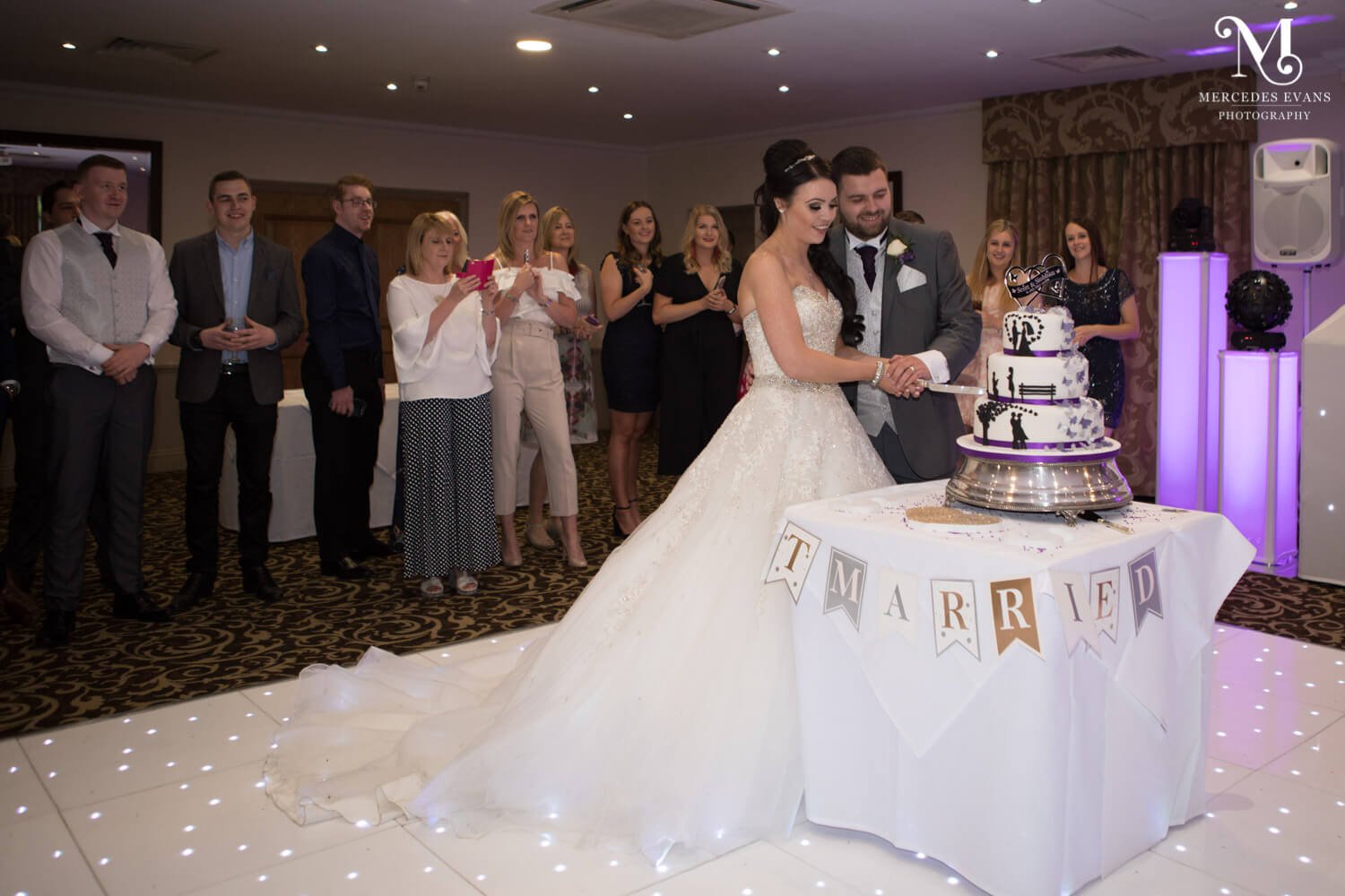 The bride and groom cut their wedding cake on the dance floor in the Frimley Suite at Frimley Hall Hotel