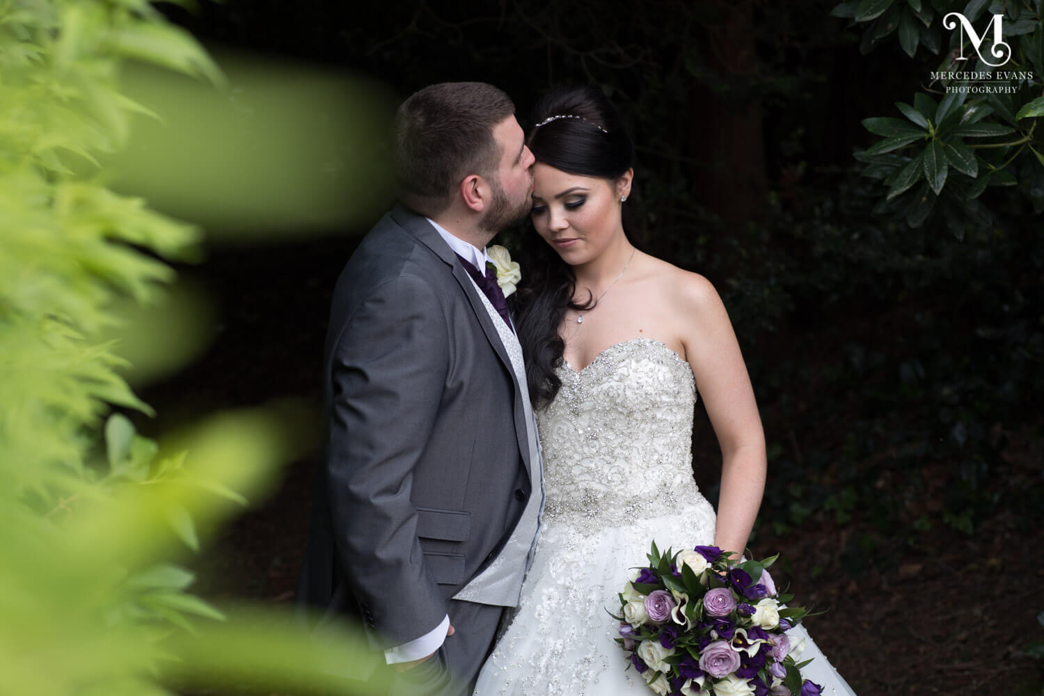 the groom kisses his new wife's forehead during their couple photo shoot at frimley Hall Hotel