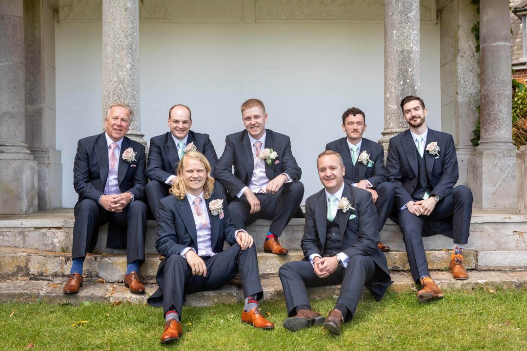 The groom and his groomsmen pose for a seated group photo in the folly at Highfield Park