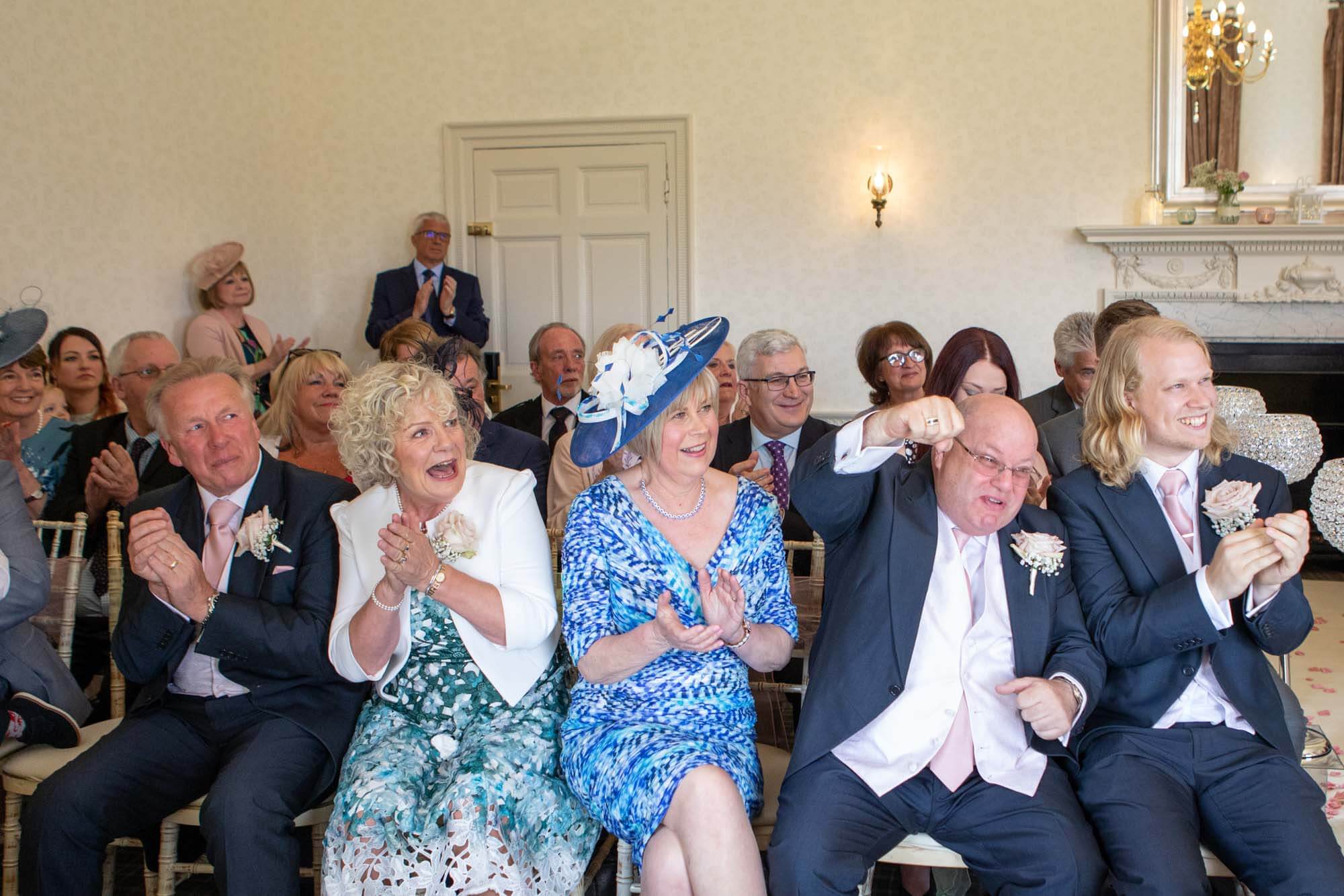 the father of the bride punches the air as all of the guests celebrate the marriage