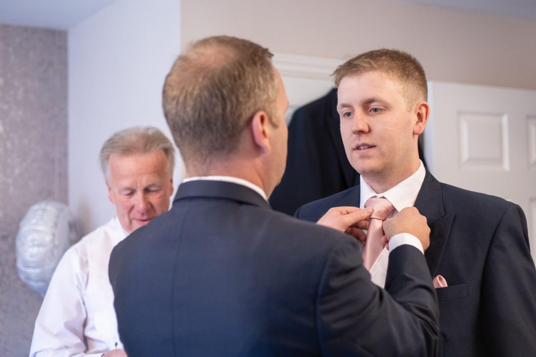 The father of the groom straightens his son's tie