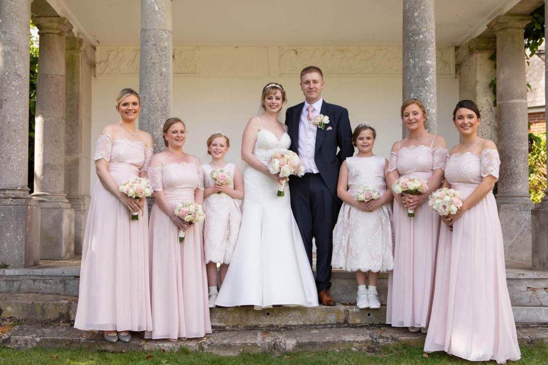 The bride and groom pose with the maid of honour, bridesmaids and flower girls