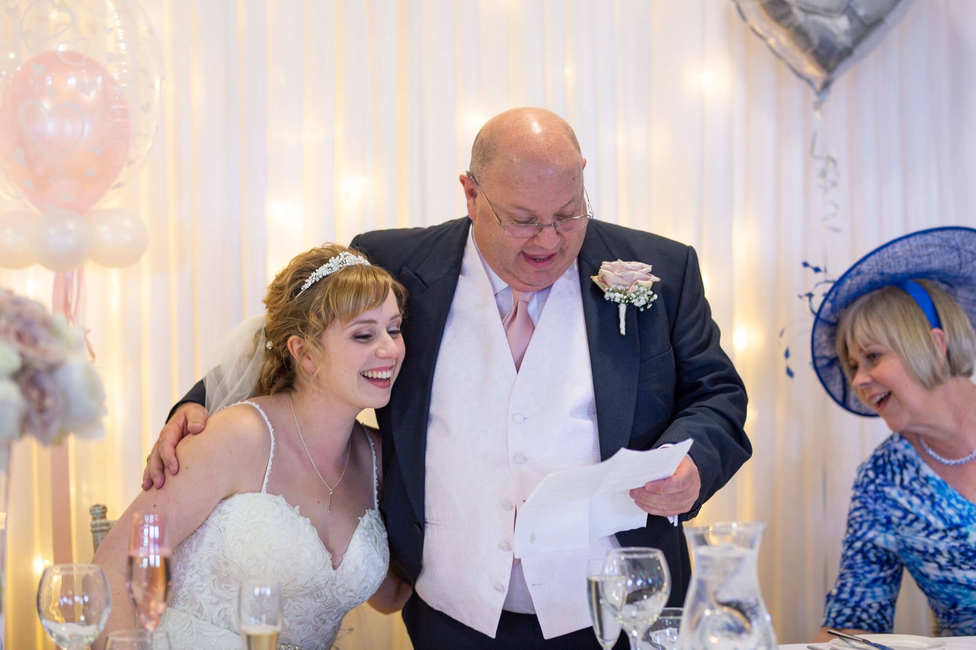 The father of the bride hugs his daughter during his speech