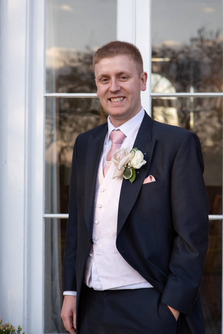 the groom stands outside for a portrait before his wedding at Highfield park