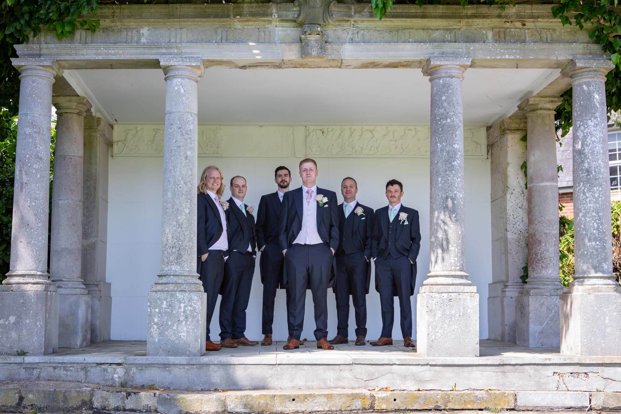 The groom and groomsmen pose in the folly at highfield park before the wedding