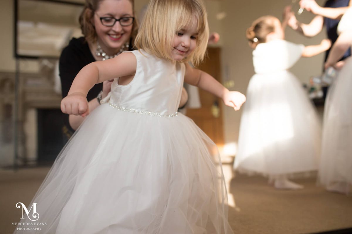 tiny flower girl tries to escape as an adult does up her dress in the Seymour room at the Elvetham hotel