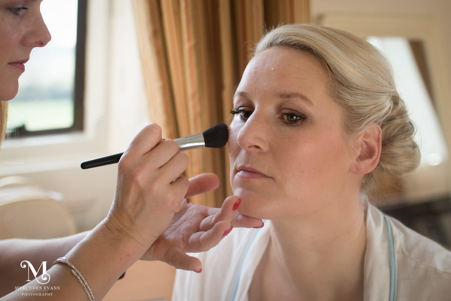 the make up artist applies the bride's blusher in the seymour room at the elvetham