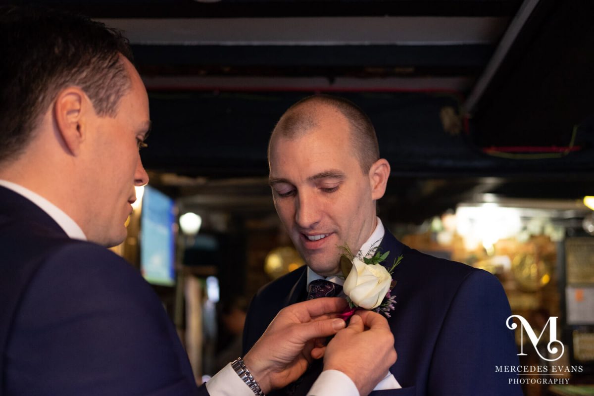 The best man helps the groom with his buttonhole