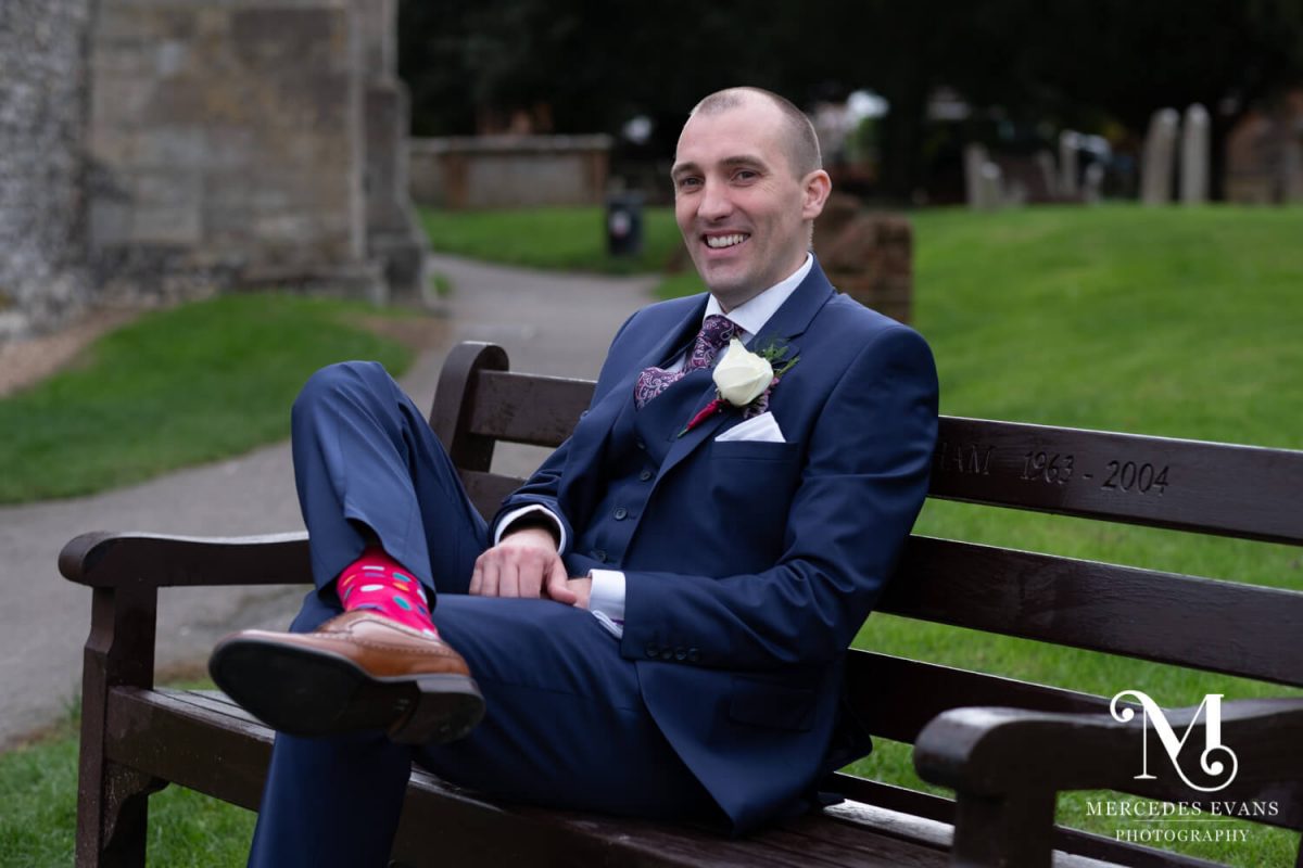 The groom relaxes on a bench before the ceremony