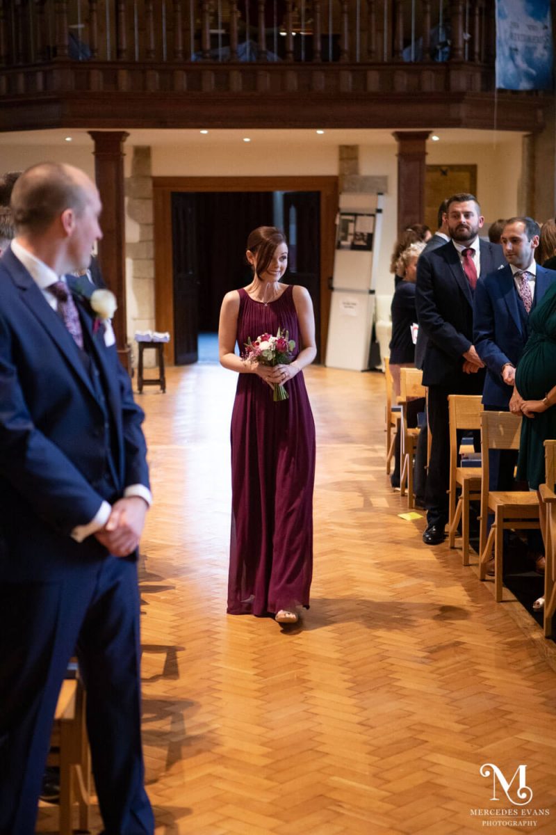 a bridesmaid walks down the aisle and makes a face at the guests