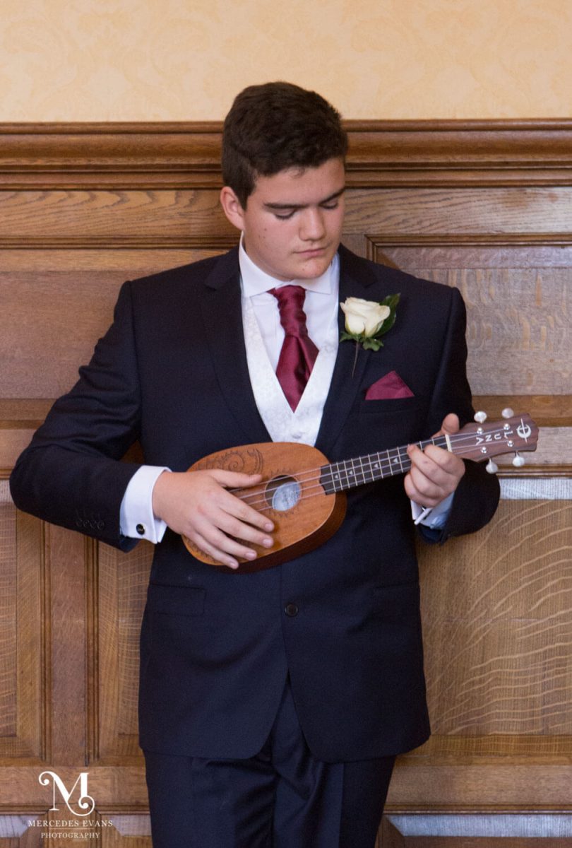 a young man plays the eukele during the signing of the register at a wedding at the Elvetham Hotel