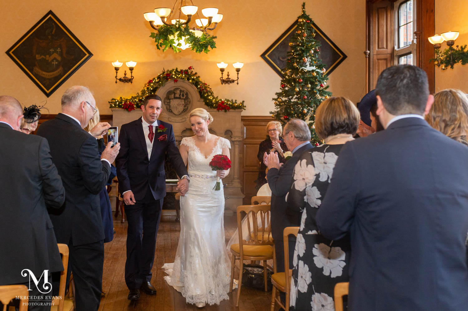 The newly married couple walk back down the aisle after their wedding ceremony in the Oak Room at the Elvetham
