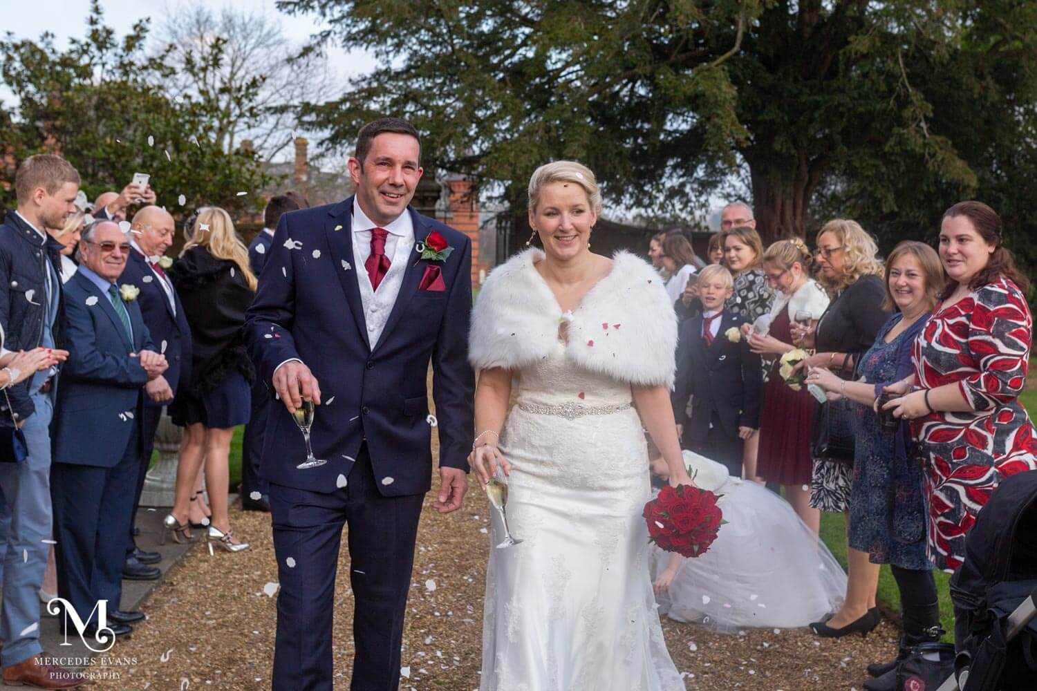 the newly weds walk as guests throw confetti in the gardens of the Elvetham Hotel
