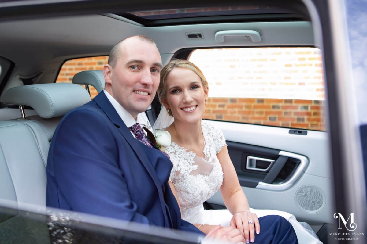the newly married couple sit in the wedding car after the ceremony