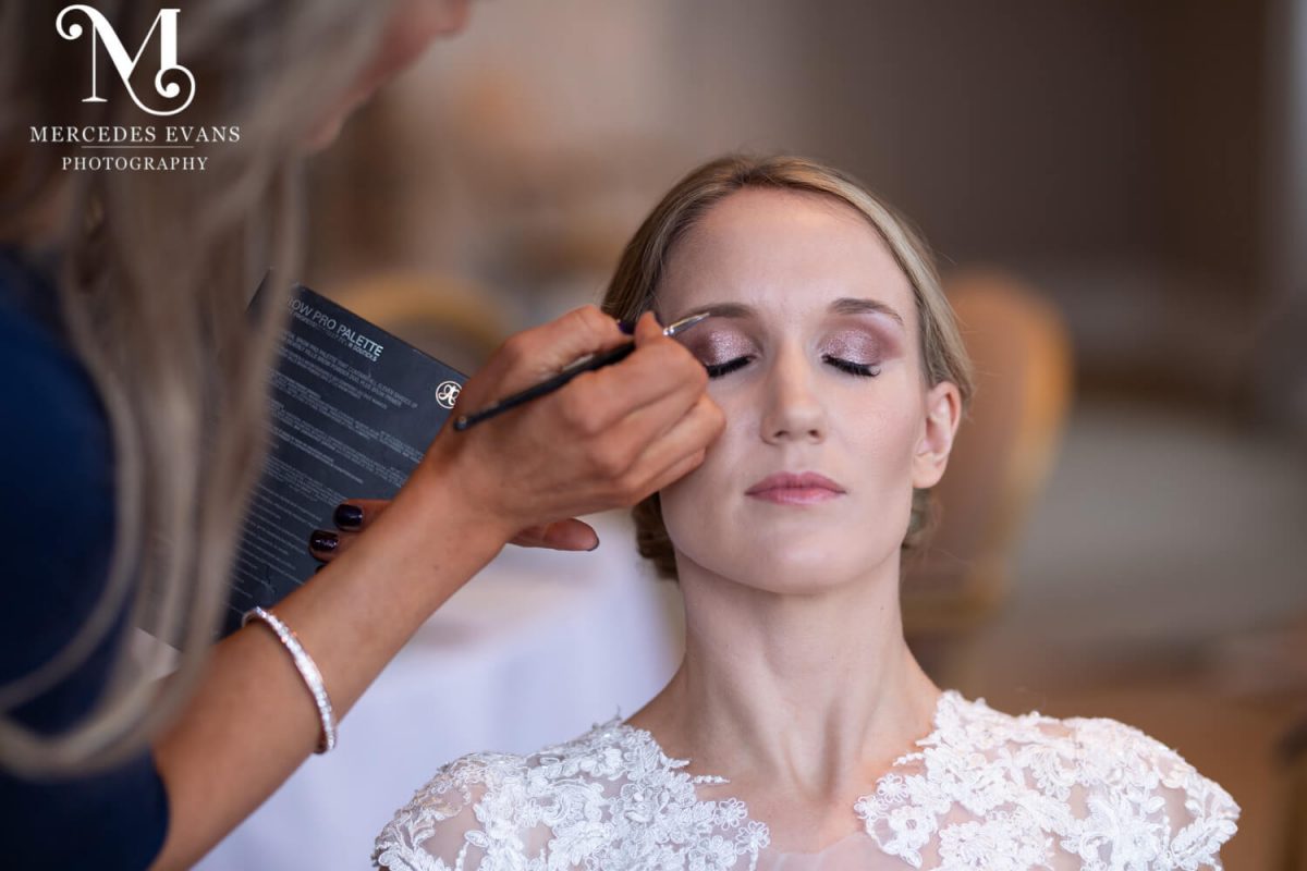 the make up artist applies eyeshadow to the bride
